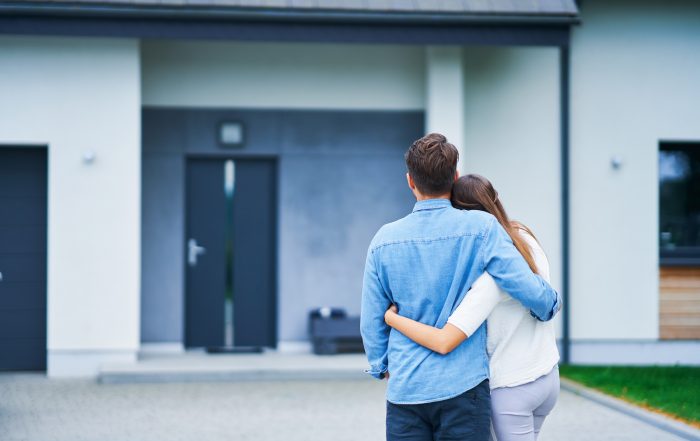 Couple in front of one-family house in modern residential area